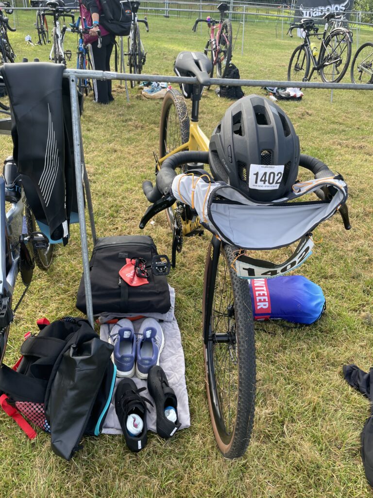 Meine eingerichtete Wechselzone: Helm und Startnummernband liegen auf dem Lenker bereit, links nebern Fahrrad stehen die Schuhe. 